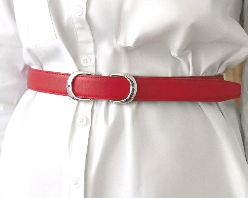 A close-up of a woman wearing a white button-front dress or shirt with a bright red, Stanhope belt and silver buckle at the waist.